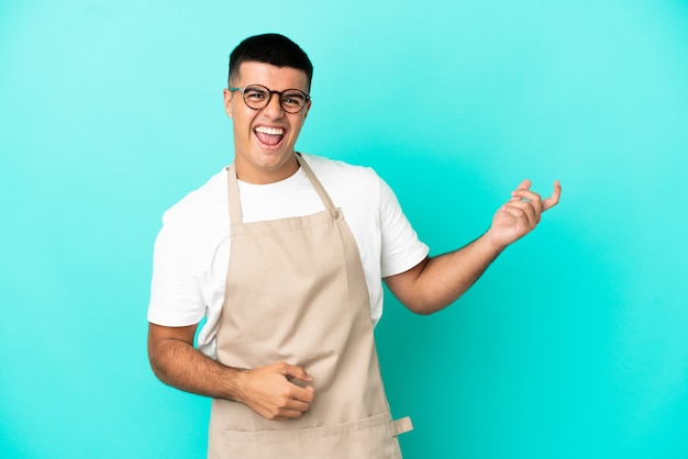 Garçom de restaurante sobre fundo azul isolado fazendo gesto de guitarra