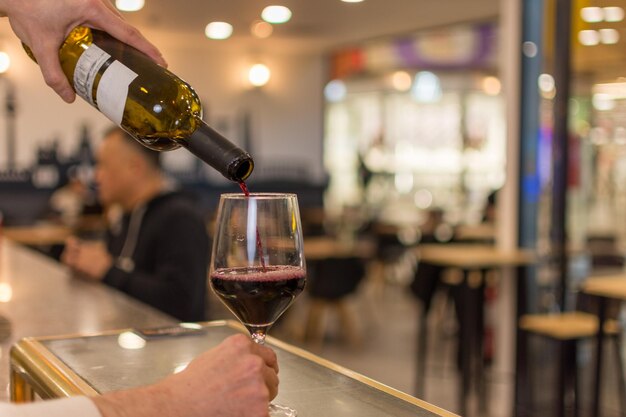 Foto garçom derramando vinho em copos sommelier com uma garrafa de vinho vermelho degustação de vinho no restaurante