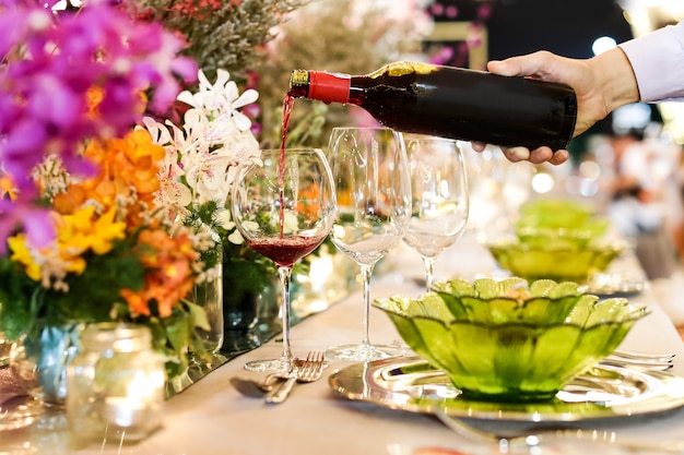 Garçom, derramando vinho em vidro no casamento de luxo