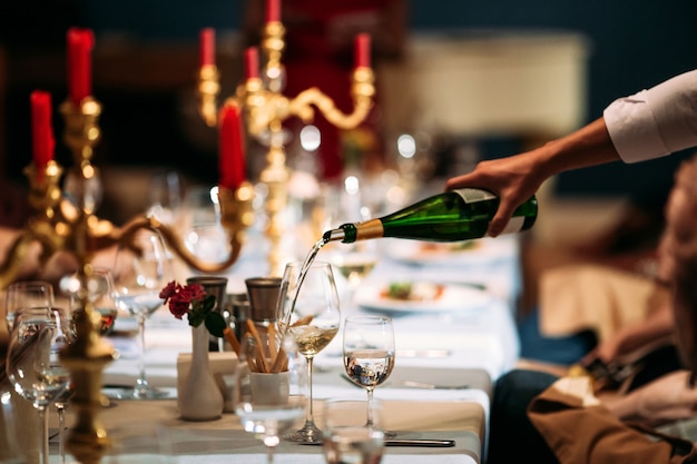 Garçom mão derramando vinho em um copo servido mesa