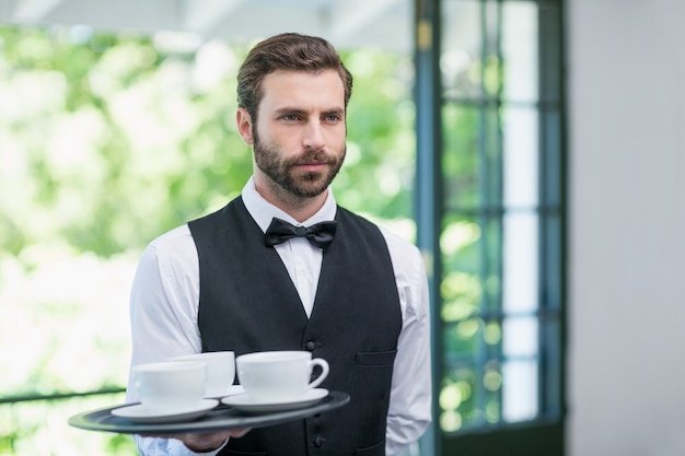 Garçom masculino, segurando a bandeja com copos de café
