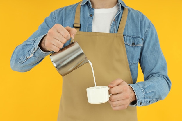 Garçom ou barista despeje leite em fundo amarelo