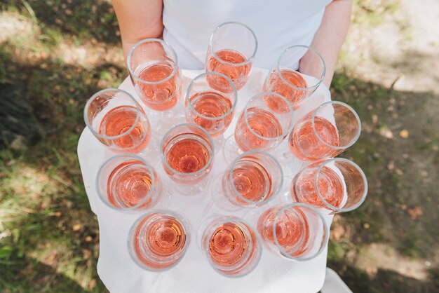 Garçom ou servidor segurando uma bandeja de copos de vinho espumante rosa para os convidados em uma recepção de casamento