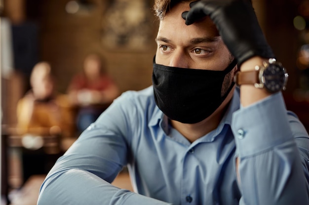 Garçom perturbado com máscara protetora pensando em algo em um café