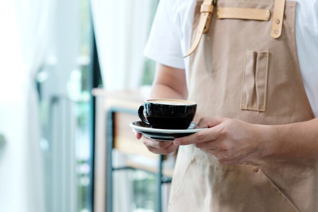 Garçom que serve uma xícara de café no conceito de café, comida e bebida