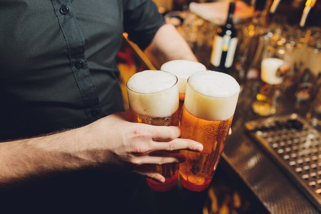 Foto garçom servindo copos de cerveja fria na bandeja