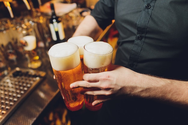 Garçom servindo copos de cerveja gelada na bandeja.