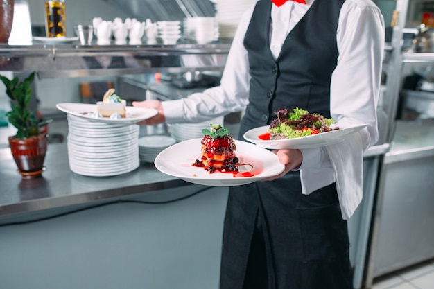 Garçom, servindo em movimento de plantão no restaurante. O garçom leva pratos