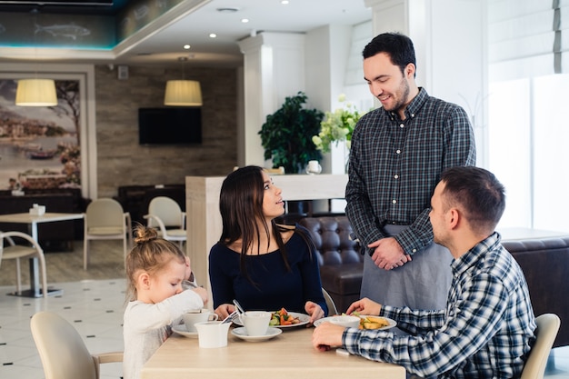 Garçom servindo família em restaurante