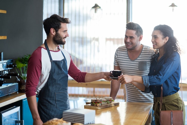 Foto garçom, servindo um café ao cliente no balcão