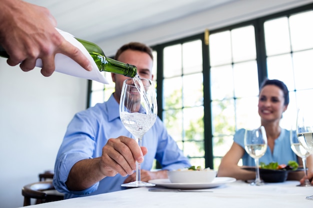 Garçom servindo vinho para o grupo de amigos enquanto almoça