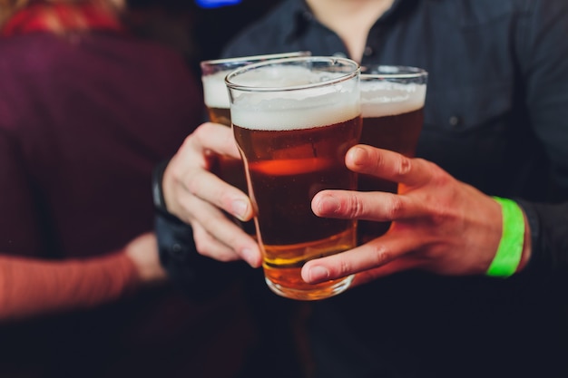 Garçom tem copos de cerveja nas mãos em um bar ou pub