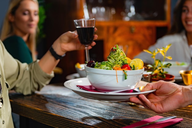 Foto garçom trazendo um prato com refeição vegetariana