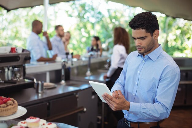 Garçom usando tablet digital em café ao ar livre