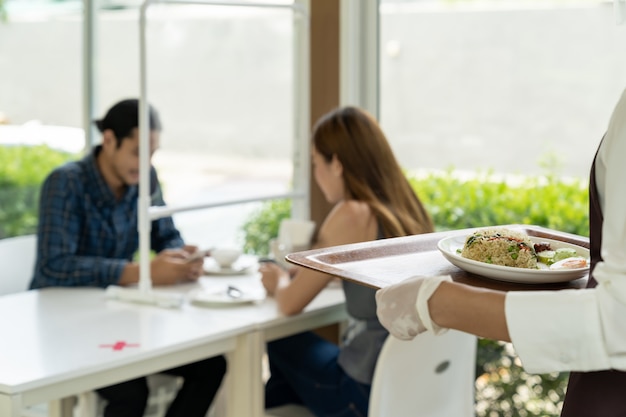 Garçonete asiática servindo comida novo normal.