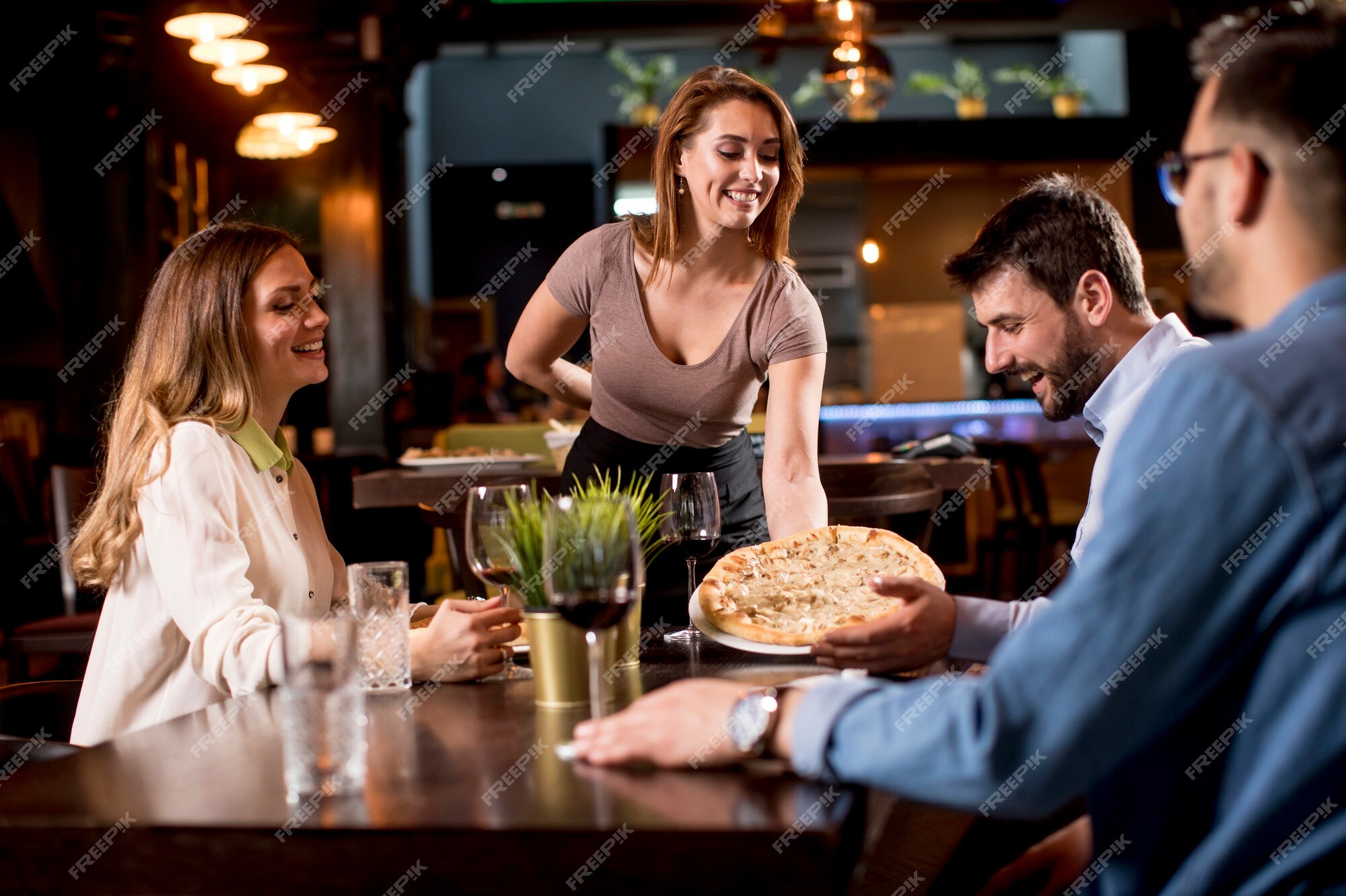 Garçonete bonita servindo grupo de amigas com comida no restaurante