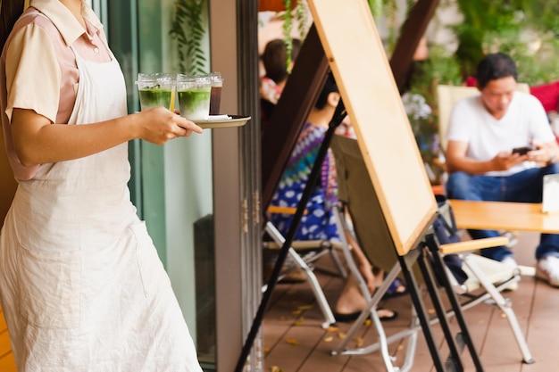 Garçonete com avental servindo matcha latte gelado ao cliente no café