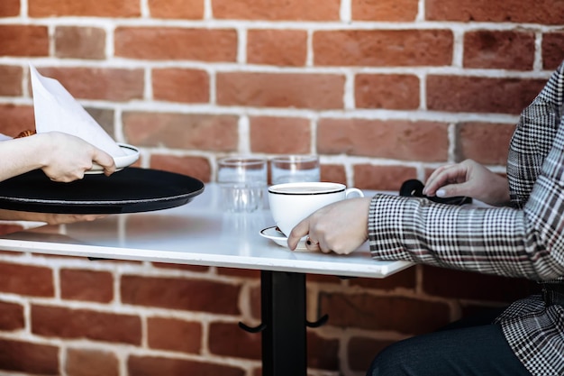 Garçonete em uma cafeteria ao ar livre traz uma xícara de café