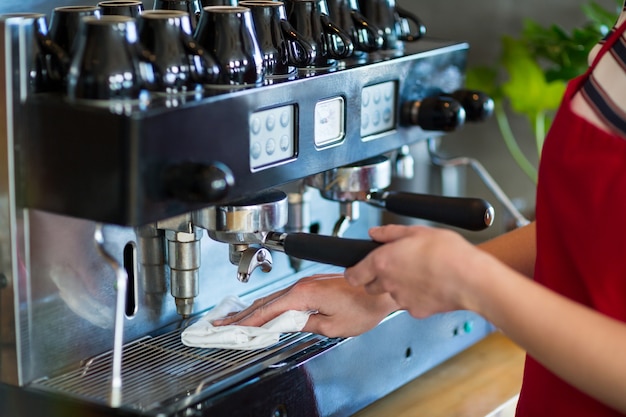 Foto garçonete, limpando a máquina de café expresso com guardanapo na cafeteria