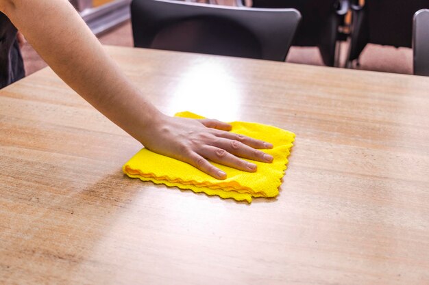 Garçonete limpando a mesa do bar com um pano amarelo