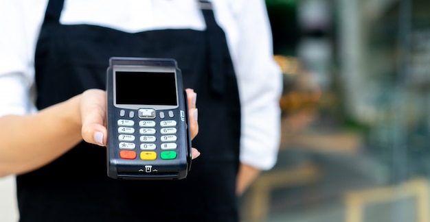 garçonete mão mostrar máquina de dinheiro bancário eletrônico para receber a compra do cliente no restaurante