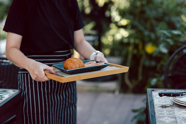 Garçonete servindo croissants na cafeteria ao ar livre