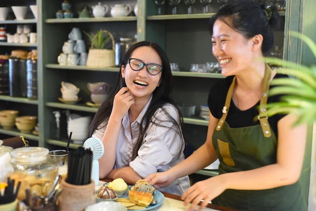 Garçonete vietnamita sorridente servindo um sorvete de cliente com waffle na cafeteria vietnamita