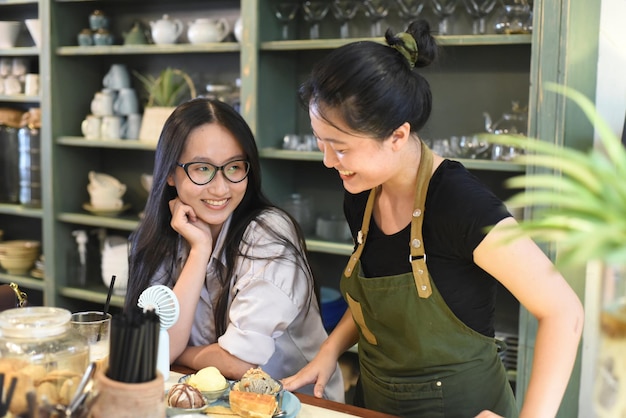 Garçonete vietnamita sorridente servindo um sorvete de cliente com waffle na cafeteria vietnamita