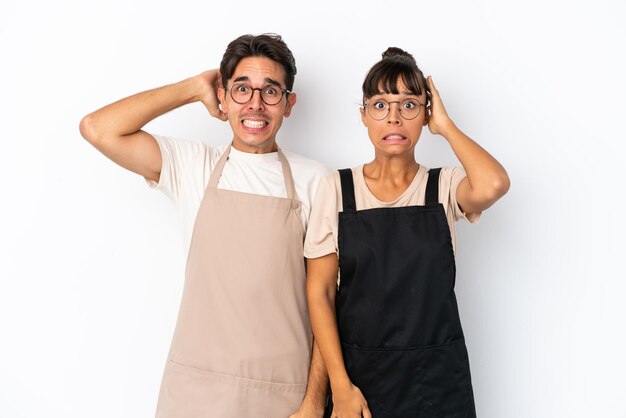 Garçons de restaurante de raça mista isolados em fundo branco pegam as mãos na cabeça porque tem enxaqueca