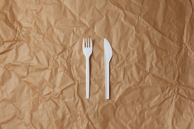 Garfo branco reciclável reutilizável, faca feita de amido de milho ou aveia em papel artesanal amarrotado marrom, espaço de cópia