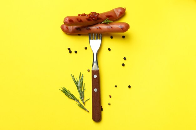 Foto garfo com linguiça grelhada em fundo amarelo