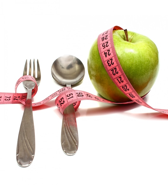 Garfo de colher e maçã é amarrado por uma fita para medir a dieta