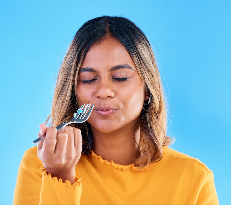 Foto garfo de mulher e bolo no estúdio para comer sobremesa satisfeito ou olhos fechados de felicidade por fundo azul menina modelo e feliz por lanche de doces ou sabor de teste para refeição ou dieta por pano de fundo