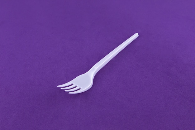 Garfo de utensílios de plástico branco isolado em roxo