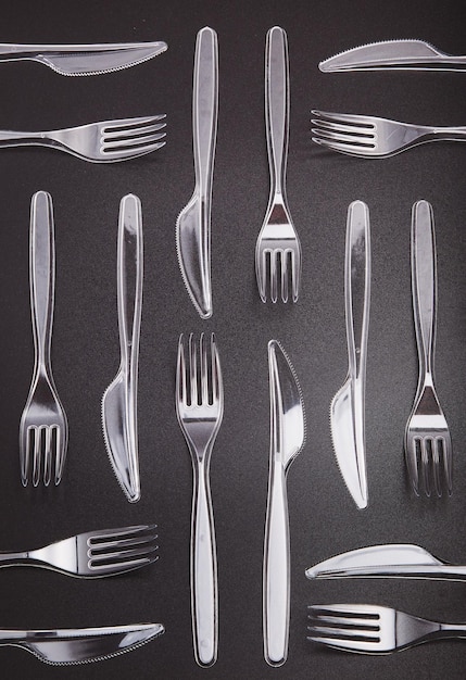 Foto garfos y cuchillos de plástico sobre un fondo gris que recogen residuos plásticos para su reciclaje