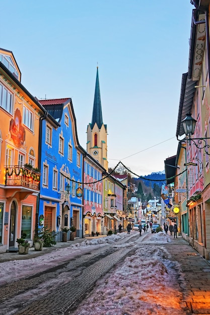 Garmisch-Partenkirchen, Alemanha - 6 de janeiro de 2015: Pináculo de Maria Himmelfahrt Assunção dia igreja na rua decorada para o Natal, Garmisch-Partenkirchen, Alemanha. Pessoas no fundo