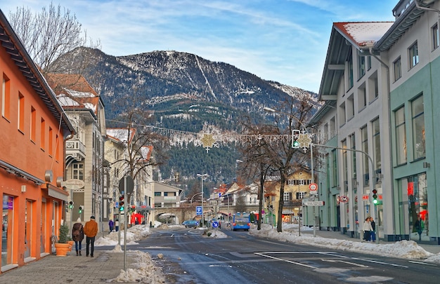 Garmisch-Partenkirchen, Alemania - 6 de enero de 2015: Calle pequeña ciudad alpina con casas típicas, gente caminando por la calle, montañas en el fondo. Garmisch-Partenkirchen, Baviera, Alemania