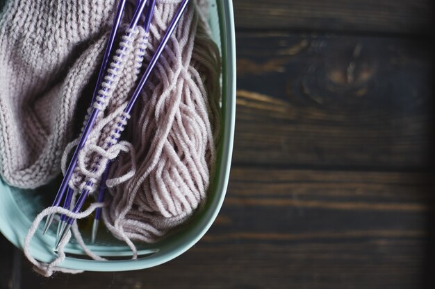 Garn in spulen und stricknadeln auf holztisch. home hobbys. handgestrickte socke mit nadeln und wollknäuel