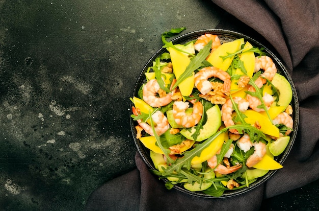 Garnelen-Mango-Avocado-Salat mit Walnuss-Spinat und Rucola Gesunde Ernährung Lebensmittelkonzept Draufsicht grauer Hintergrund