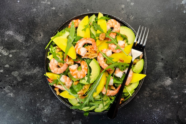 Garnelen-Mango-Avocado-Salat mit Walnuss-Spinat und Rucola Gesunde Ernährung Lebensmittelkonzept Draufsicht grauer Hintergrund