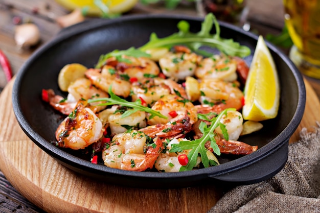 Garnelen Shrimps gebraten in Knoblauchbutter mit Zitrone und Petersilie auf hölzernen Hintergrund.