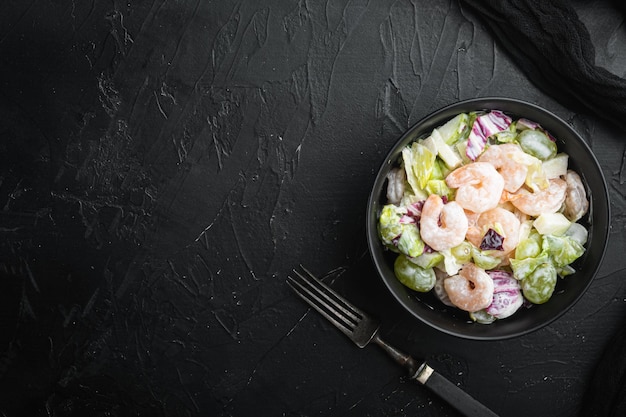 Garnelencocktail mit Salat, Kirschtomaten, Dressing, Dill-Set, mit Sauce Apfel und Traube, auf schwarzem Steinhintergrund, Draufsicht flach, mit Kopienraum für Text