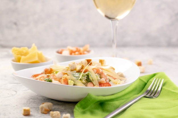 Garnelensalat mit frischem Gemüse, Käse und Croutons. Eine große Portion wird in einem tiefweißen Teller serviert.