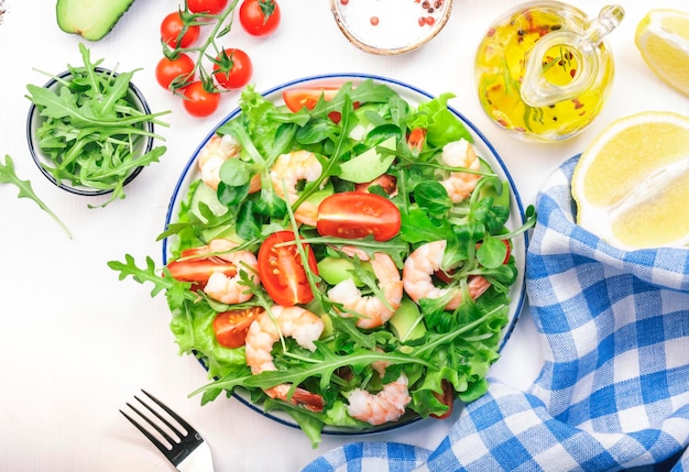 Garnelensalat mit Kirschtomaten, Rucola, Avocado und Öl-Zitronen-Dressing auf weißem Hintergrund Draufsicht