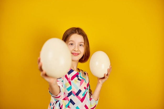 Garota adolescente brincalhona feliz segurando ovos de avestruz