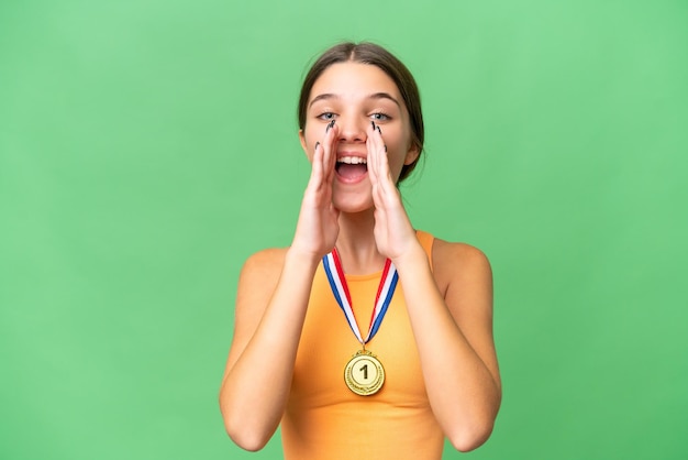 Garota adolescente caucasiana com medalhas sobre fundo isolado gritando e anunciando algo