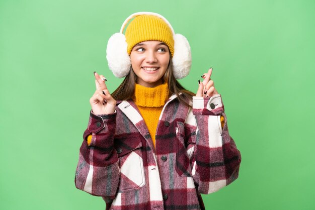 Garota adolescente caucasiana usando regalos de inverno sobre fundo isolado com dedos cruzando