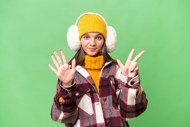 Garota adolescente caucasiana usando regalos de inverno sobre fundo isolado, contando oito com os dedos