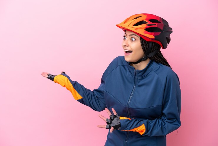 Foto garota adolescente ciclista isolada em fundo rosa com expressão de surpresa enquanto olha de lado