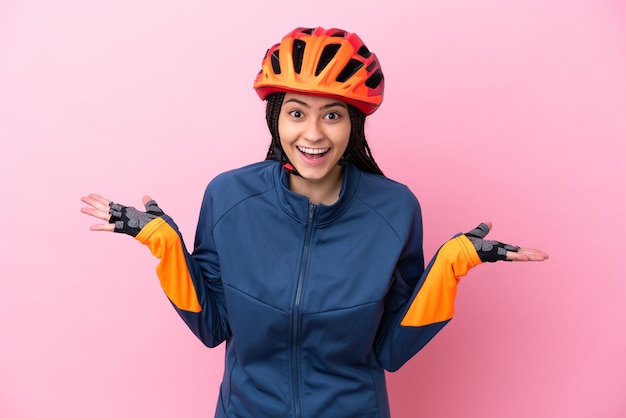 Garota adolescente ciclista isolada em fundo rosa com expressão facial chocada